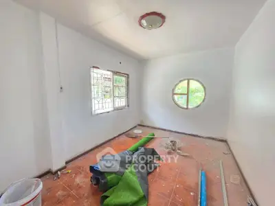 Unfinished room with round window and scattered renovation materials
