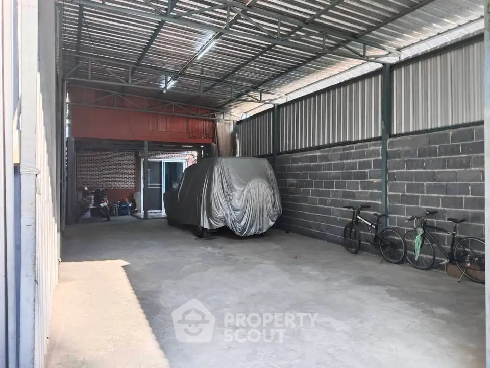 Spacious covered parking area with bicycles and a covered vehicle, ideal for secure storage.