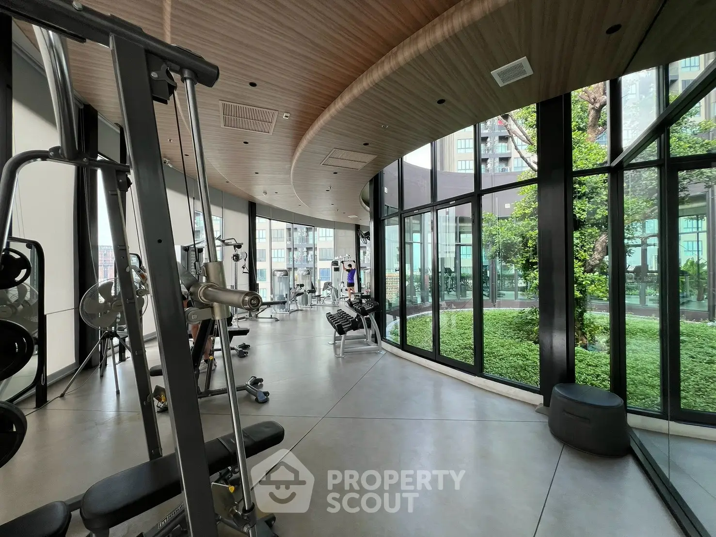 Modern gym with floor-to-ceiling windows and state-of-the-art equipment in luxury building.