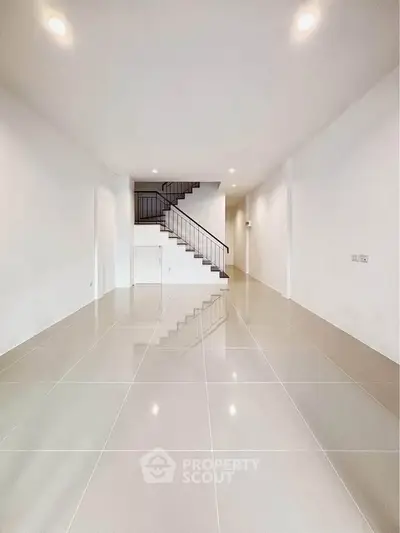 Spacious modern interior with sleek staircase and glossy tiled flooring, perfect for contemporary living.