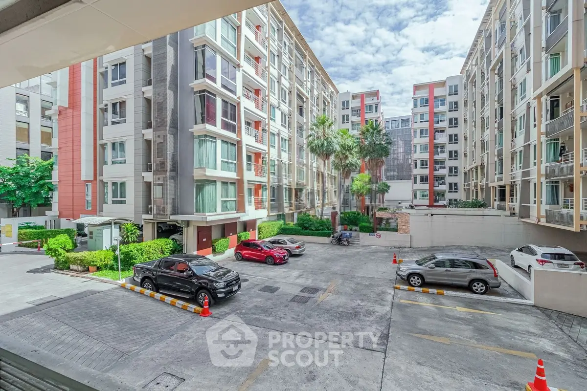 Modern apartment complex with spacious parking area and lush greenery.