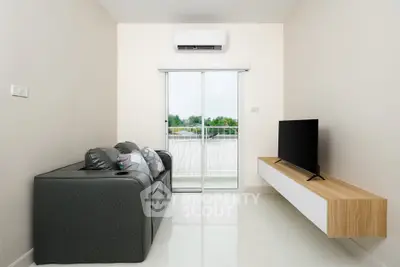 Modern living room with sleek sofa, wall-mounted TV, and balcony view.