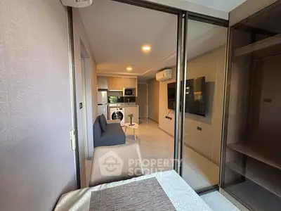 Modern apartment interior with open layout, featuring a cozy living area and sleek kitchen with appliances.