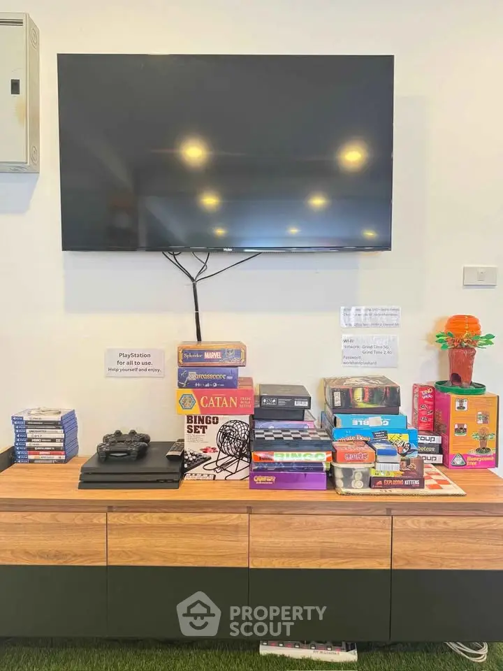 Modern living room with wall-mounted TV and board games on stylish console.