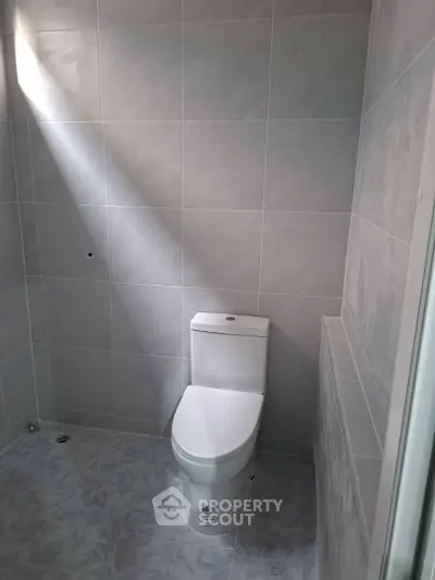 Modern minimalist bathroom with sleek white toilet and tiled walls.