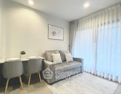 Modern living room with cozy sofa and dining area, featuring elegant decor and natural light through sheer curtains.