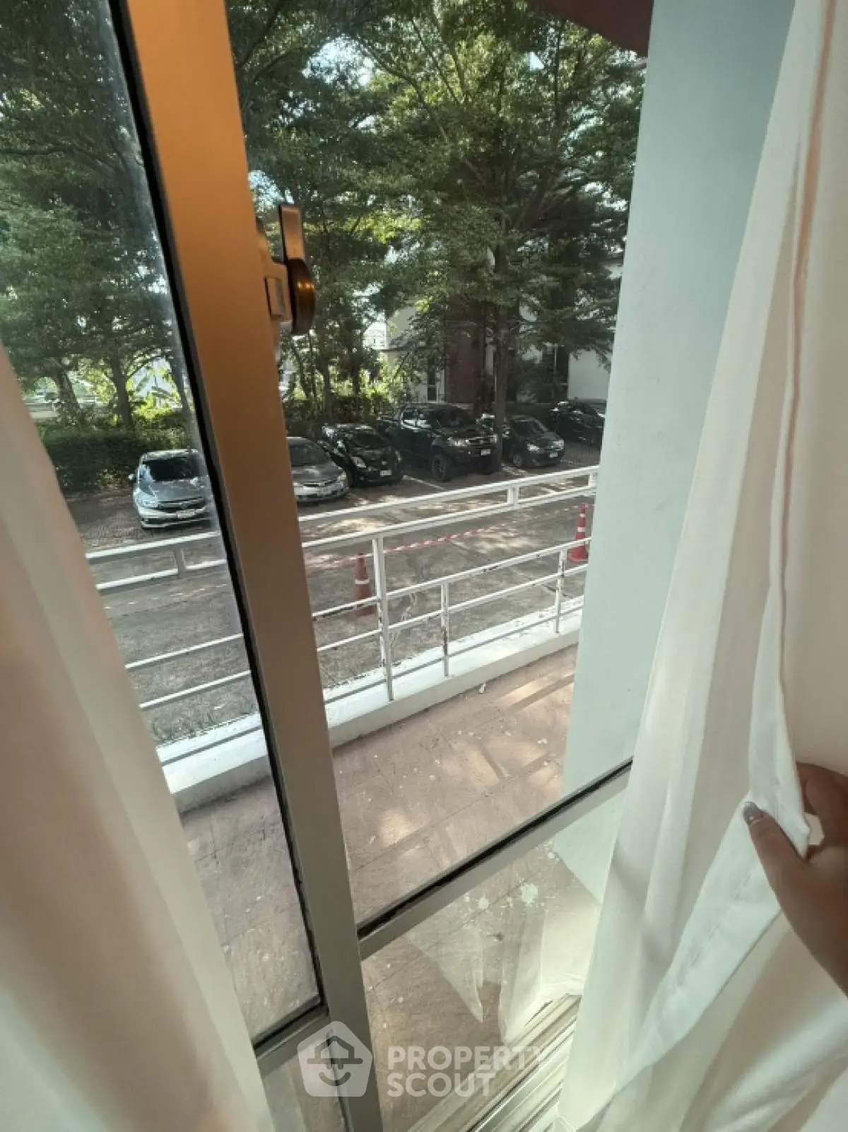 View from window overlooking parking area with trees and cars