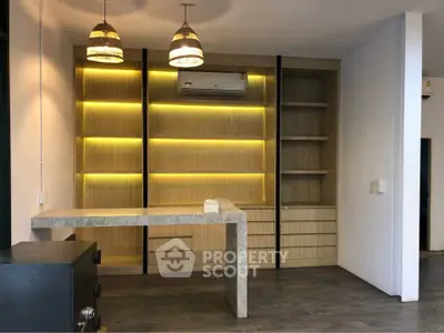 Modern kitchen with stylish lighting and built-in wooden shelves, featuring a sleek countertop and air conditioning.