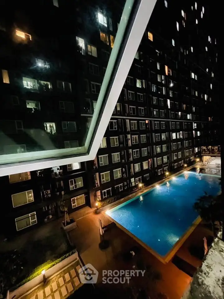 Stunning night view of a modern apartment complex with illuminated swimming pool and sleek architecture.