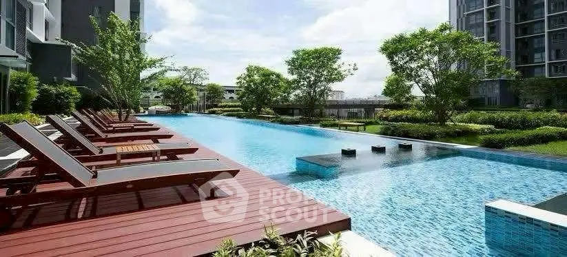 Luxurious outdoor pool with sun loungers and lush greenery in modern residential complex.