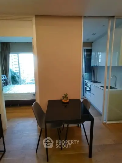 Modern apartment interior with dining area, kitchen, and bedroom view