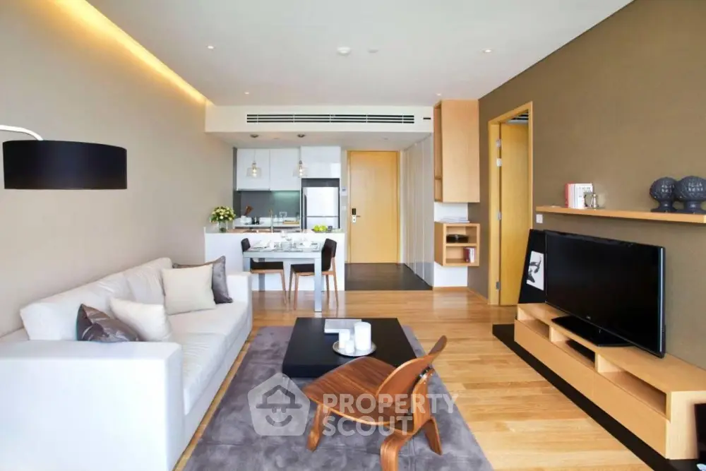 Modern living room with open kitchen, stylish furniture, and cozy ambiance.