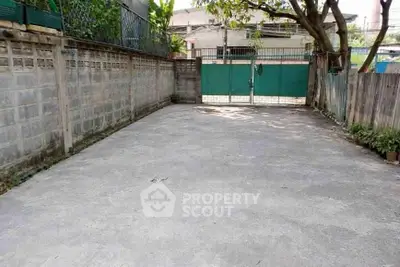 Spacious outdoor parking area with secure gated entrance and surrounding greenery.