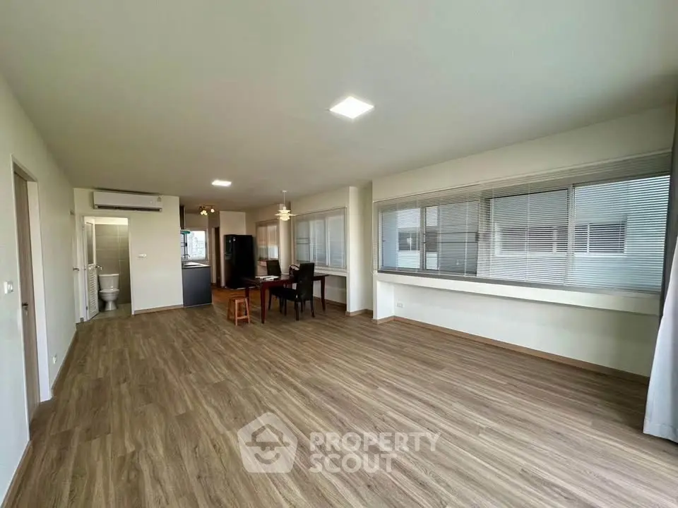 Spacious open-plan living room with modern flooring and large windows in a contemporary apartment.