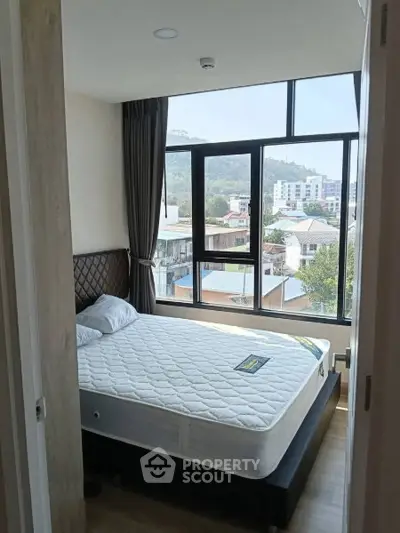 Bright bedroom with large windows offering a scenic city view, featuring a comfortable bed and modern decor.