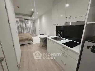 Modern studio apartment with sleek kitchen and cozy bedroom area, perfect for urban living.