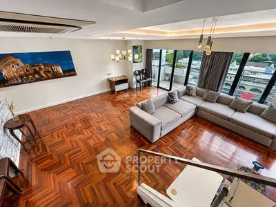 Spacious living room with elegant wooden flooring and large windows offering a stunning city view.