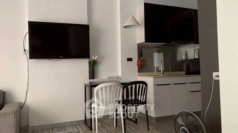 Modern compact living space with wall-mounted TV and sleek kitchen area.