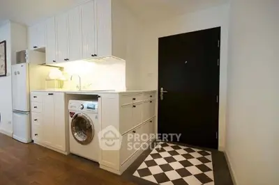 Charming kitchen with built-in washing machine and stylish black door, perfect for modern living.