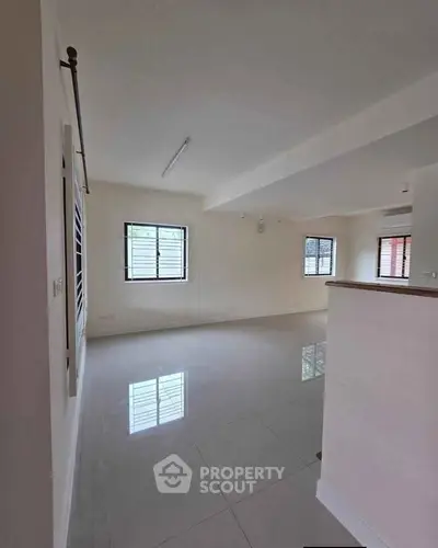 Spacious and bright living room with large windows and glossy tiled flooring.