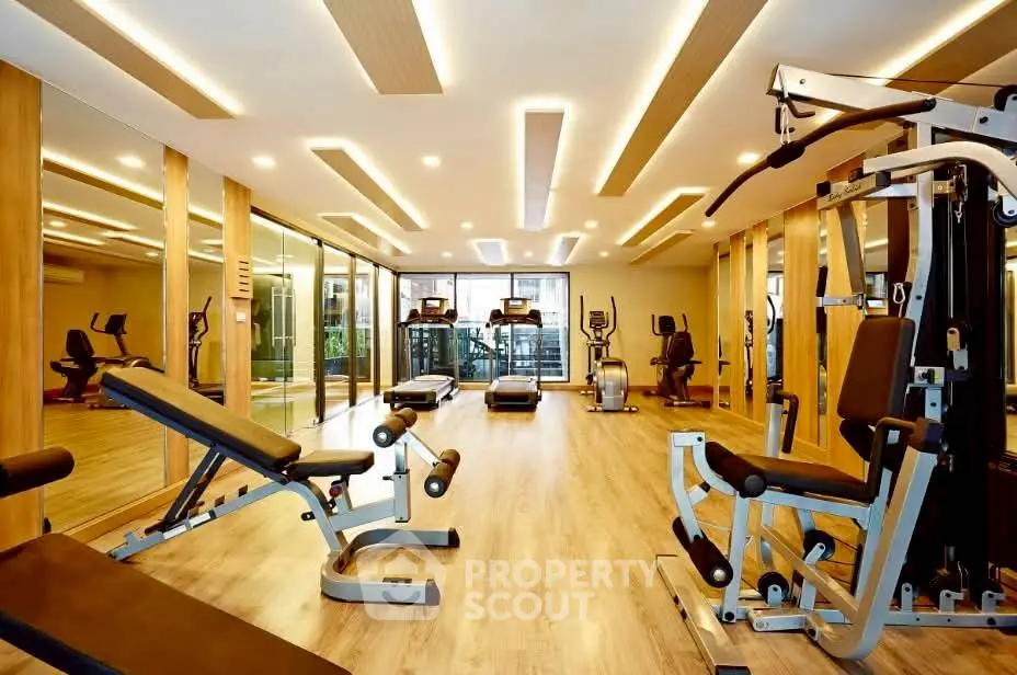Luxurious gym with modern equipment and mirrored walls in upscale residential building.