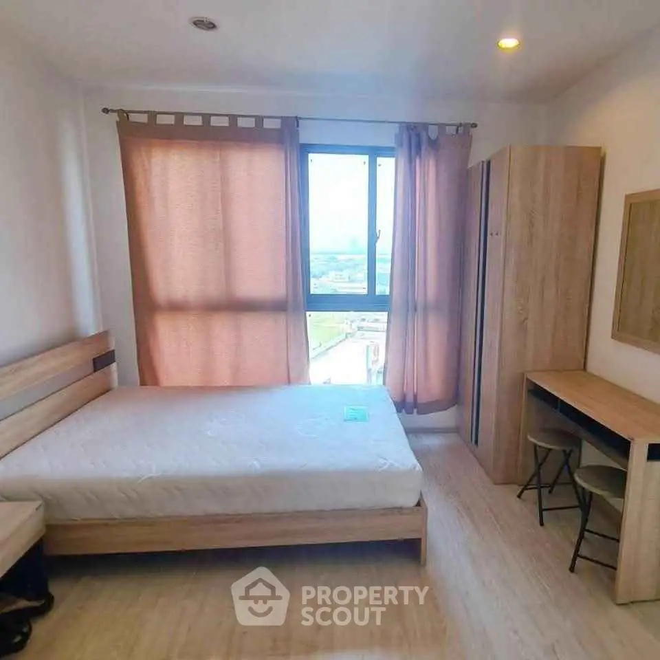 Cozy bedroom with natural light, wooden furniture, and a scenic window view.