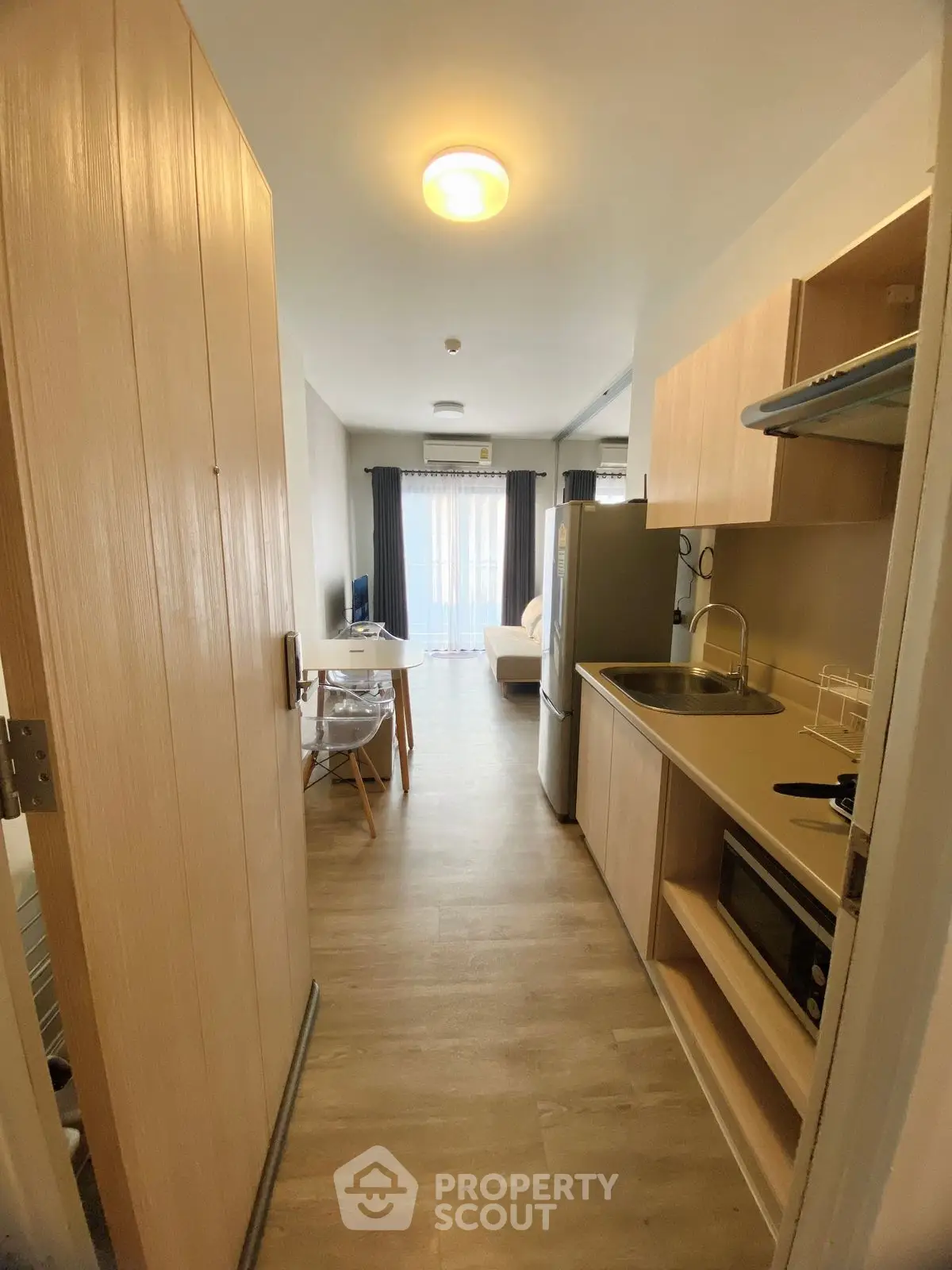 Modern open-layout kitchen with light wood cabinets and cozy living area.