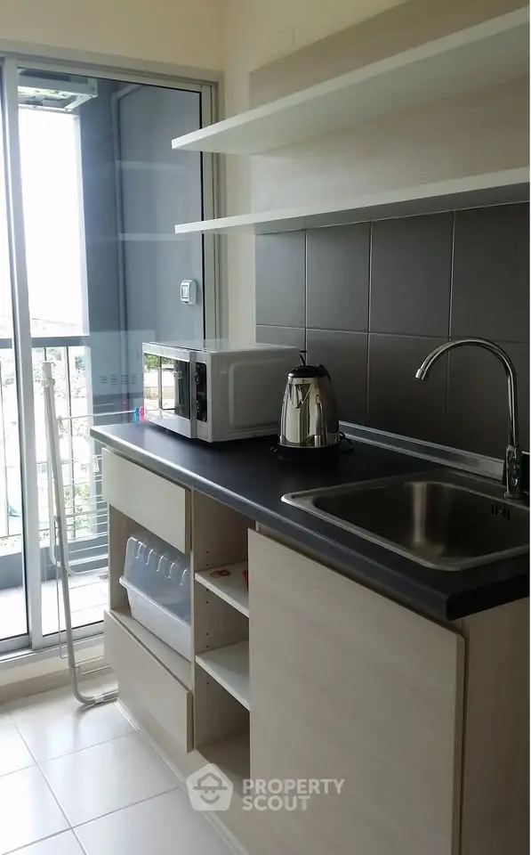 Modern kitchen with sleek cabinetry, stainless steel sink, and balcony view, perfect for urban living.