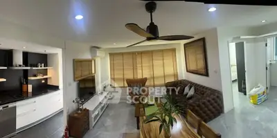 Modern living room with open kitchen, stylish decor, and cozy seating area.