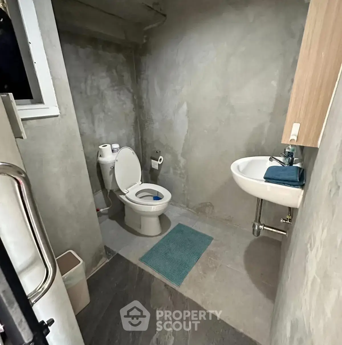 Modern minimalist bathroom with concrete walls and compact fixtures.