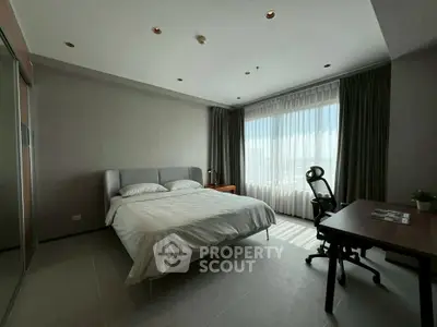 Spacious bedroom with modern decor and large window offering natural light.