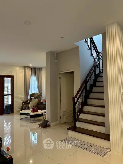 Elegant living room with staircase, plush seating, and natural light, perfect for modern family living.