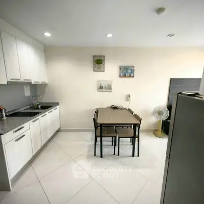 Modern kitchen with dining table and sleek cabinetry in a bright, open space.