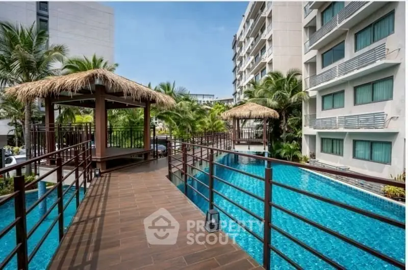 Luxurious apartment complex with stunning pool and tropical landscaping.