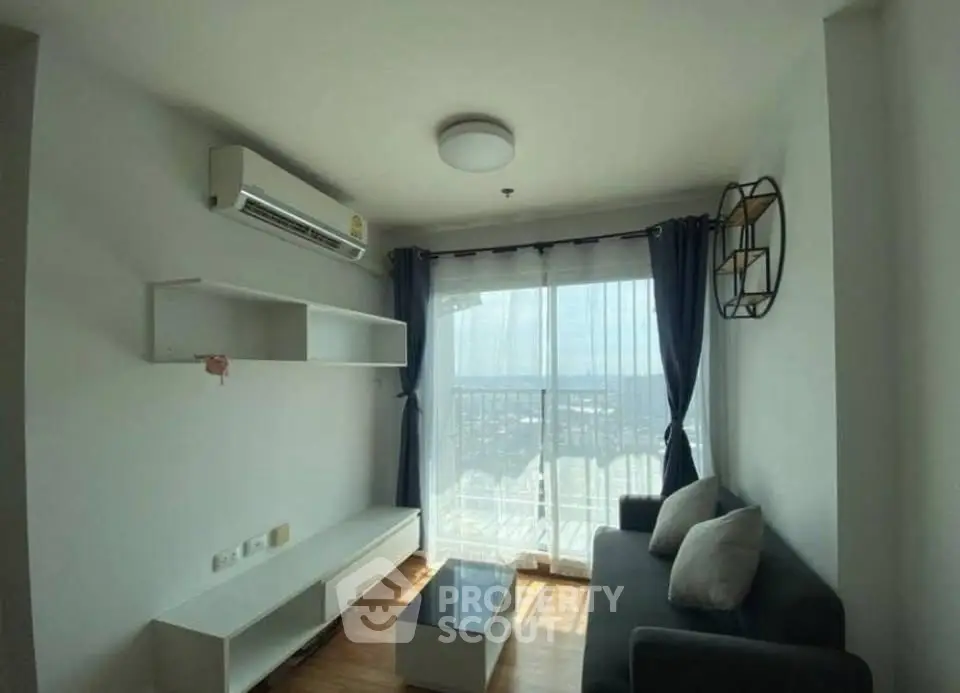 Modern living room with large window and city view, featuring sleek furniture and air conditioning.