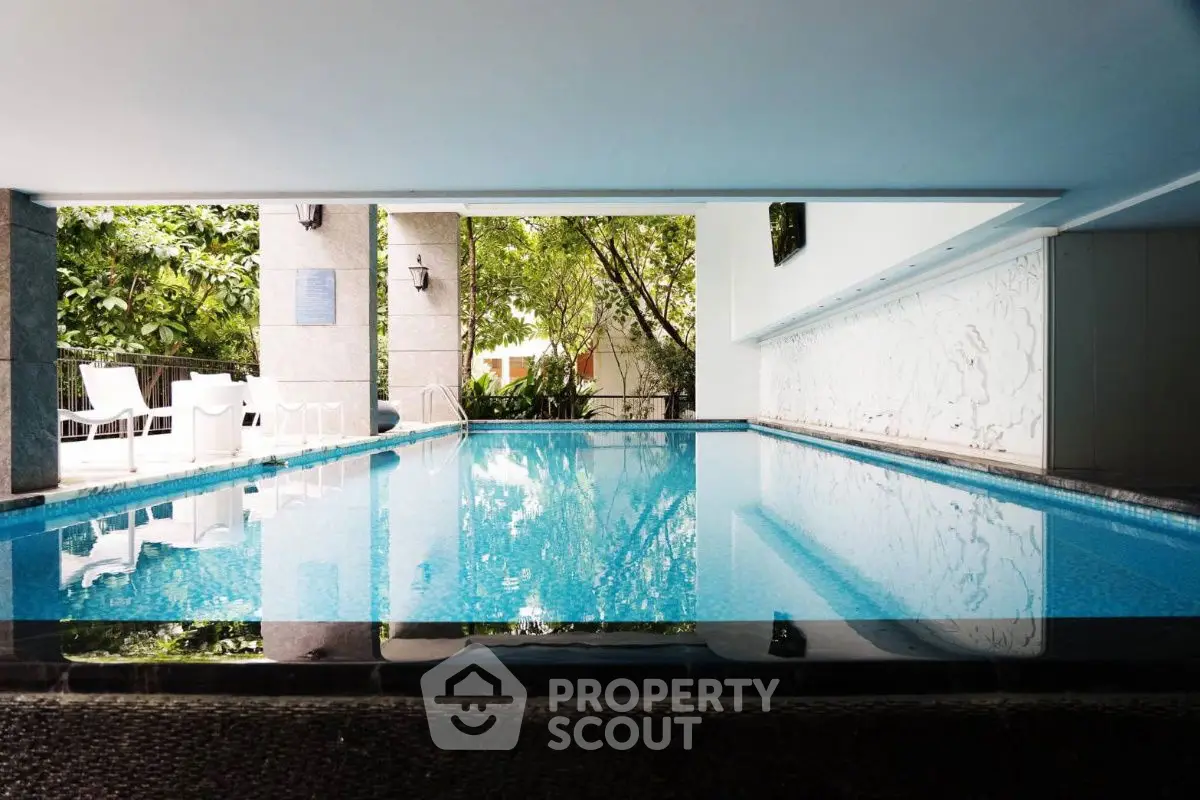 Luxurious indoor pool with modern design and lush greenery view.