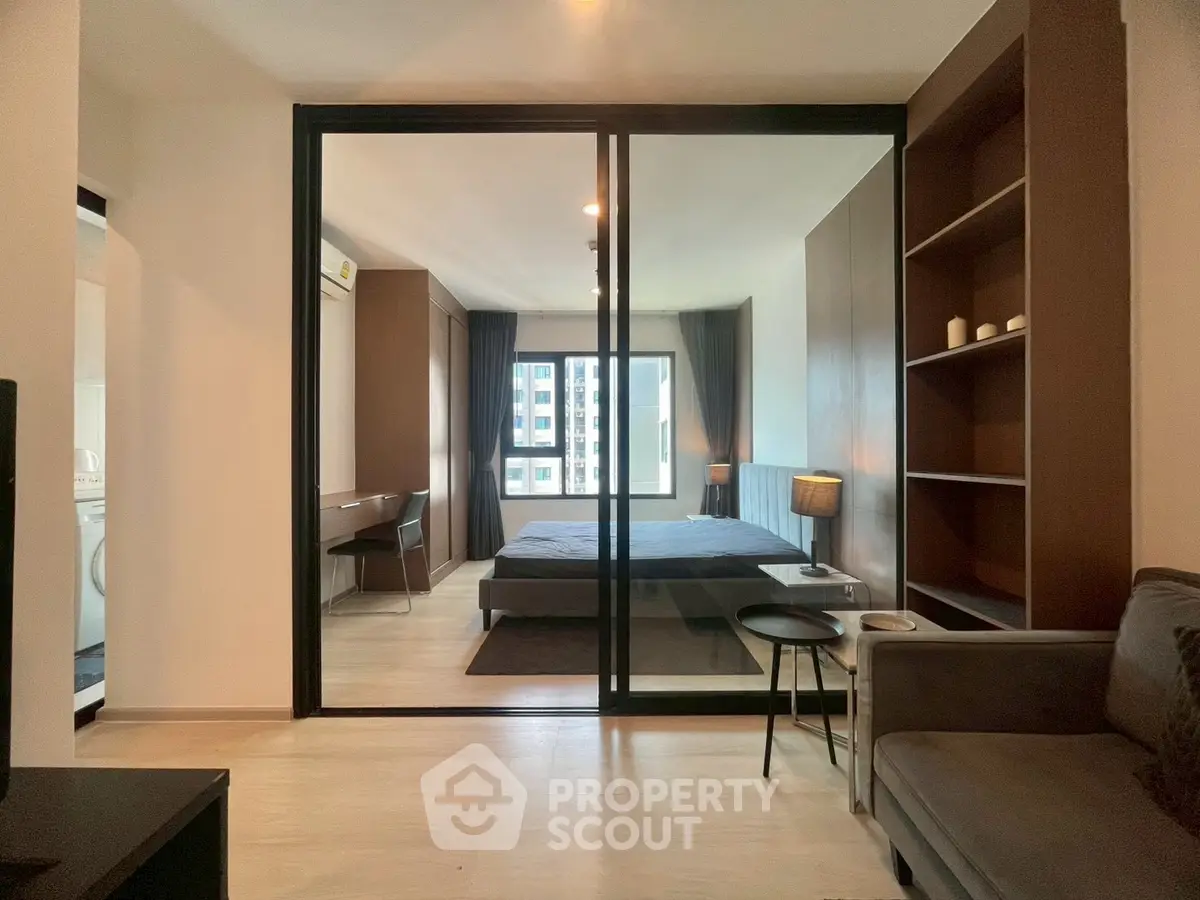 Modern bedroom with glass partition and cozy living area in stylish apartment.