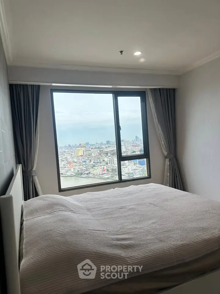 Spacious bedroom with stunning city view from large window, perfect for urban living.