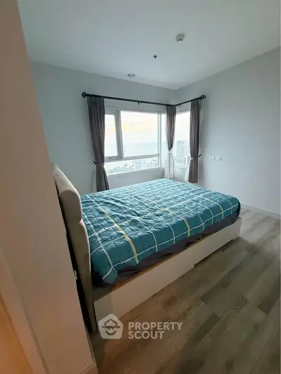 Cozy bedroom with stunning city view and large windows, perfect for relaxation and comfort.
