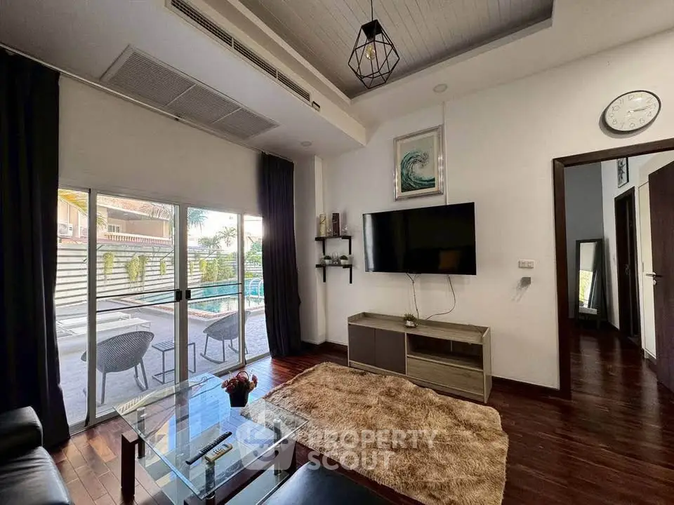 Modern living room with pool view, stylish decor, and cozy seating area.