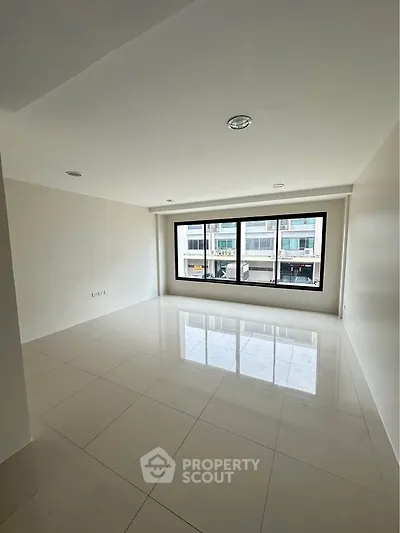 Spacious empty room with large window and glossy tiled floor, ideal for customization.