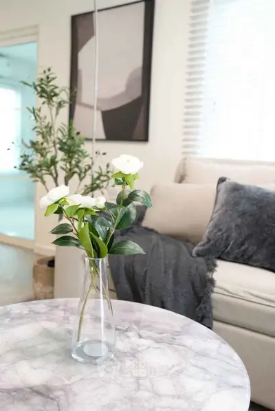 Stylish living room with modern decor and cozy ambiance, featuring a marble table and elegant floral arrangement.