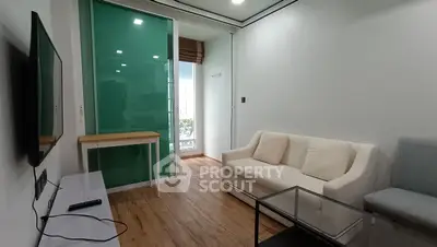 Modern living room with sleek design, featuring a cozy sofa, glass coffee table, and wall-mounted TV.