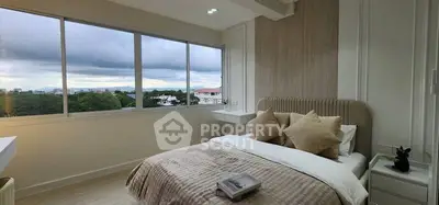 Modern bedroom with large windows and scenic view, featuring cozy bedding and stylish decor.