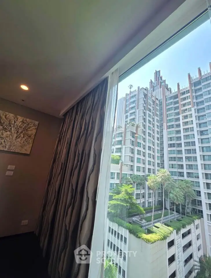 Luxurious high-rise apartment with stunning city view and lush greenery from window.