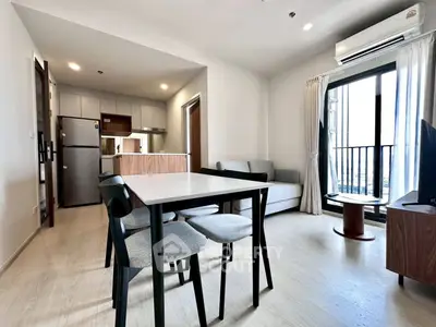 Modern open-plan living room with dining area and balcony access in a stylish apartment.
