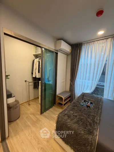 Cozy bedroom with walk-in closet and modern decor, featuring natural light and stylish furnishings.