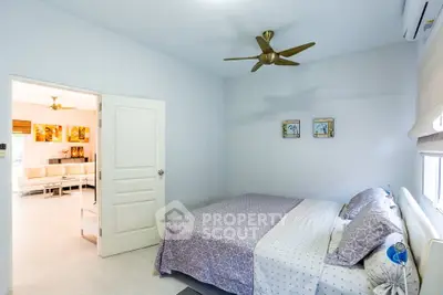 Spacious bedroom with modern decor and ceiling fan, leading to a bright living area.
