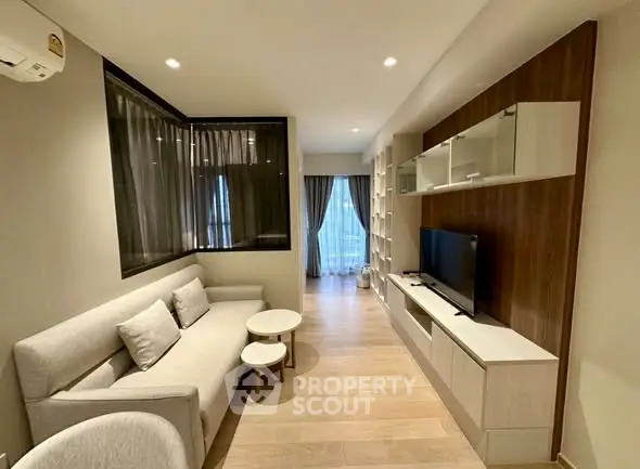 Modern living room with sleek furniture and natural light, featuring a cozy sofa and entertainment unit.