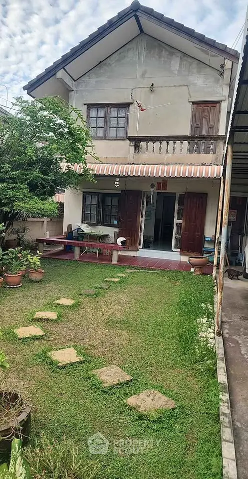 Charming two-story house with lush garden and inviting patio area.